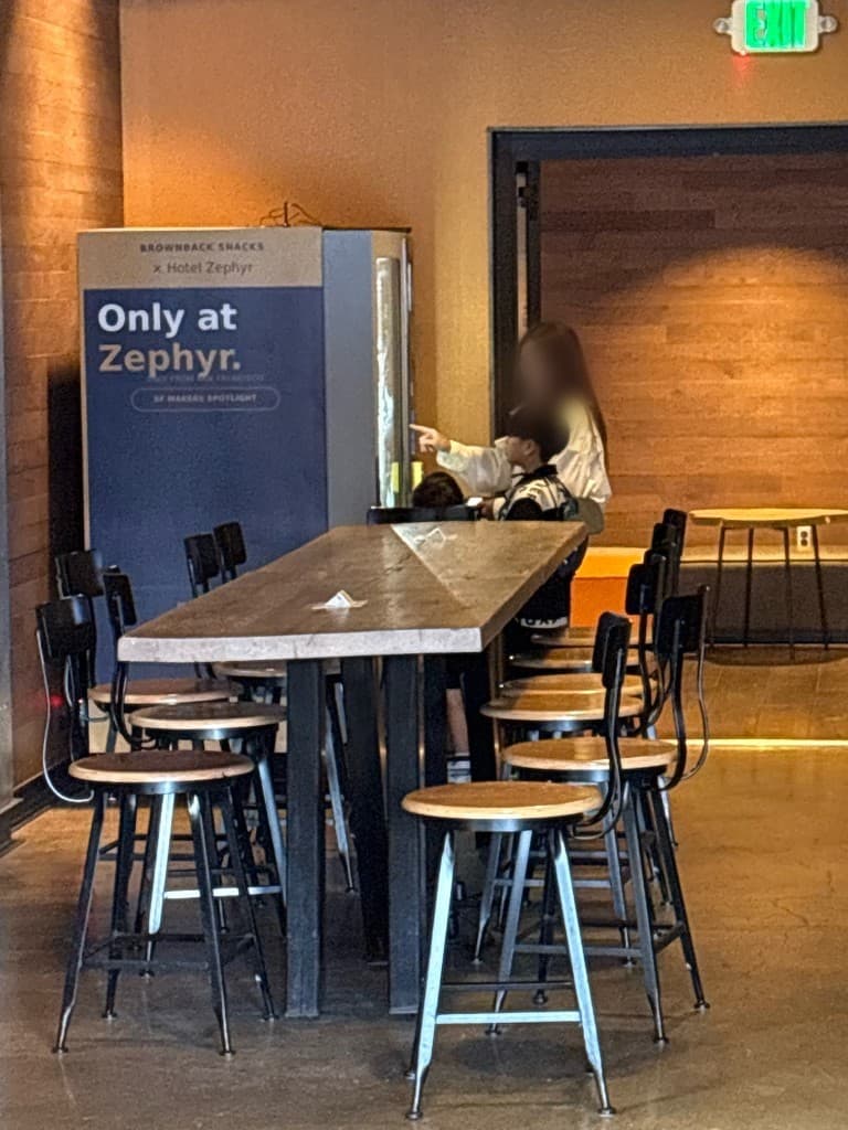 Guests using a Brownback Snacks machine in the Hotel Zephyr lobby